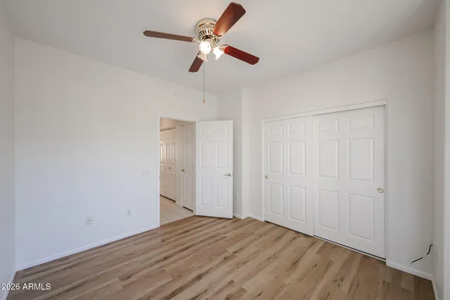 a view of empty room with wooden floor and fan