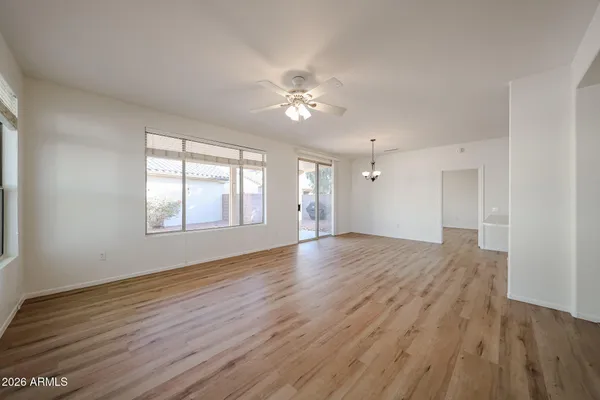 a view of an empty room with wooden floor and a ceiling fan