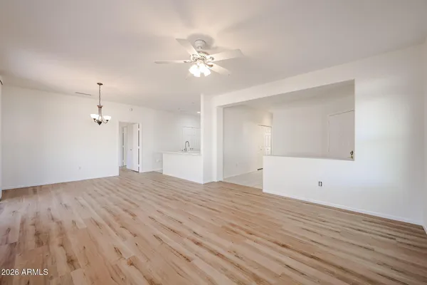 a view of an empty room with wooden floor and a ceiling fan
