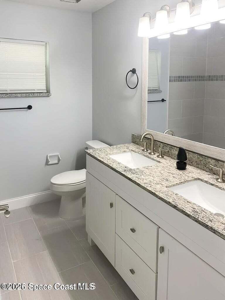 544 Plumbago Road Northwest Palm Bay, FL 32907 - Photo 12 of 14 a bathroom with a granite countertop sink a toilet and a mirror