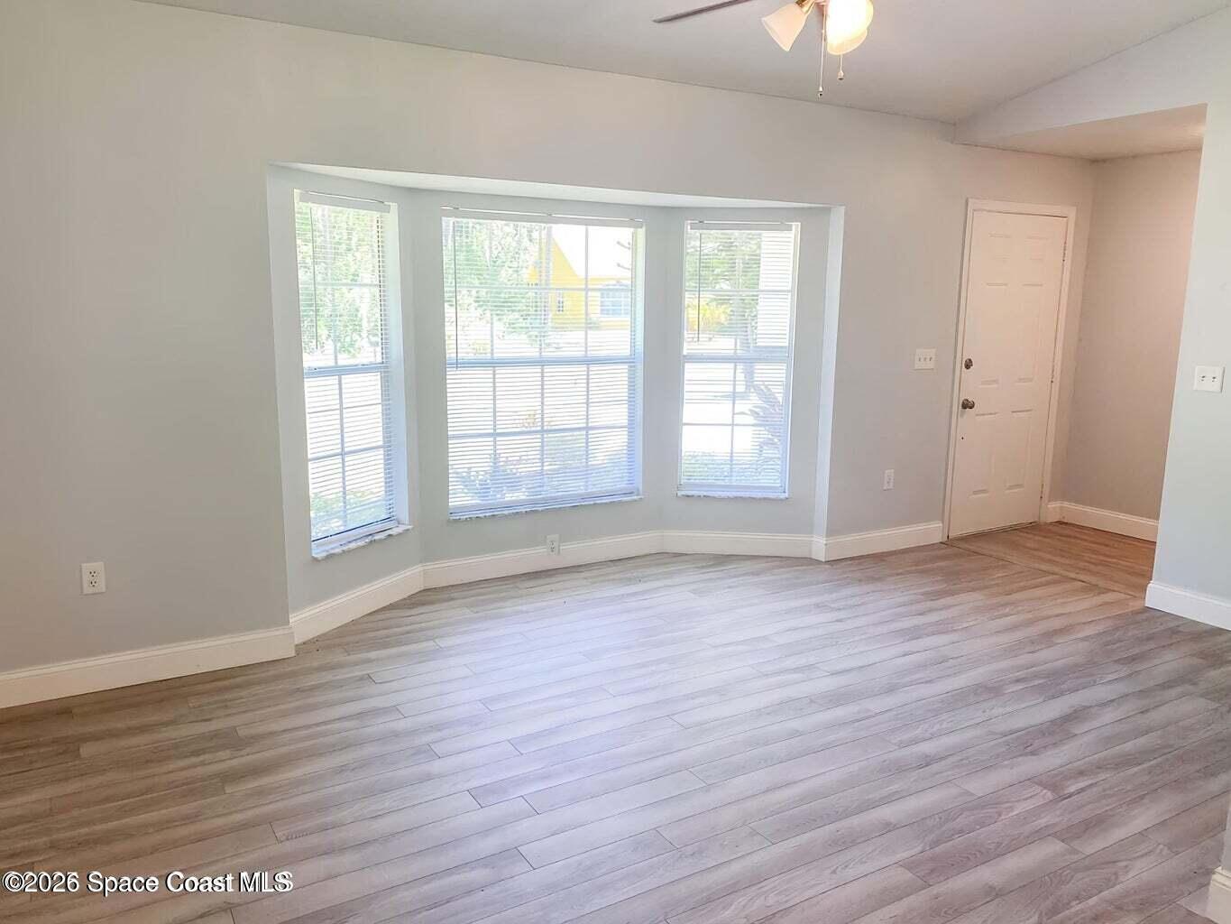 544 Plumbago Road Northwest Palm Bay, FL 32907 - Photo 4 of 14 an empty room with wooden floor and windows