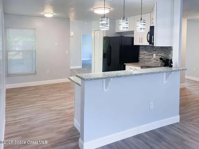 a view of a kitchen with kitchen island a sink wooden floor and a refrigerator
