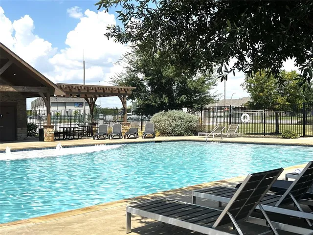 a view of a swimming pool with lawn chairs under an umbrella