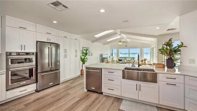 a kitchen with granite countertop a sink stainless steel appliances and white cabinets