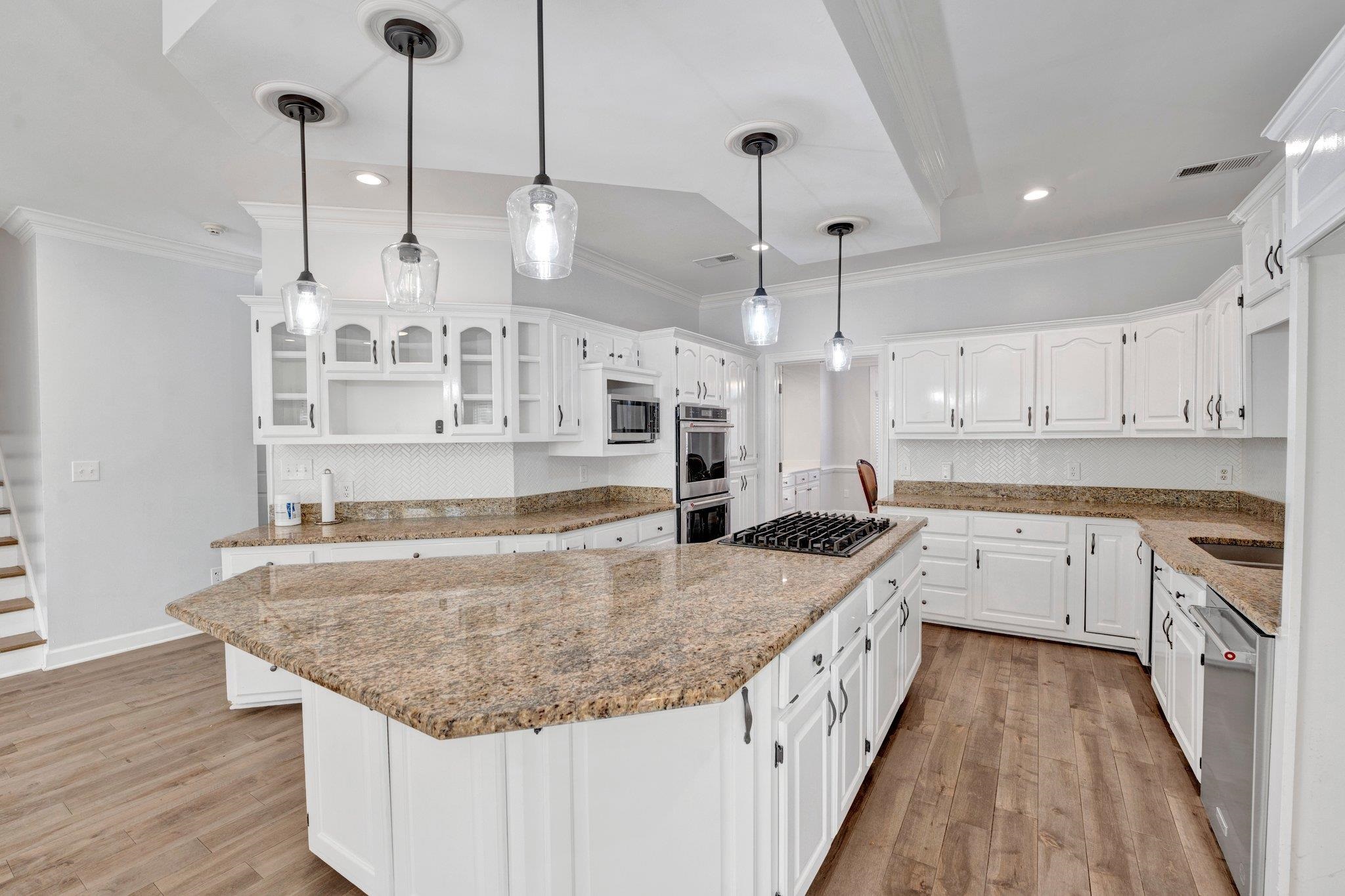 47 Summer Grove Road Memphis, TN 38018 - Photo 9 of 35 Kitchen featuring light stone countertops, a kitchen island, appliances with stainless steel finishes, crown molding, and light wood-type flooring