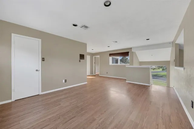 an empty room with wooden floor and windows