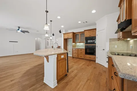 a kitchen with stainless steel appliances granite countertop a sink a stove and a wooden floors