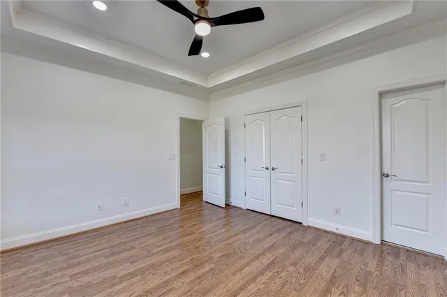 an empty room with wooden floor cabinet and windows