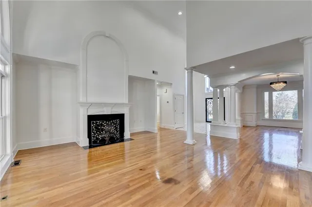 a view of an empty room with wooden floor and a fireplace