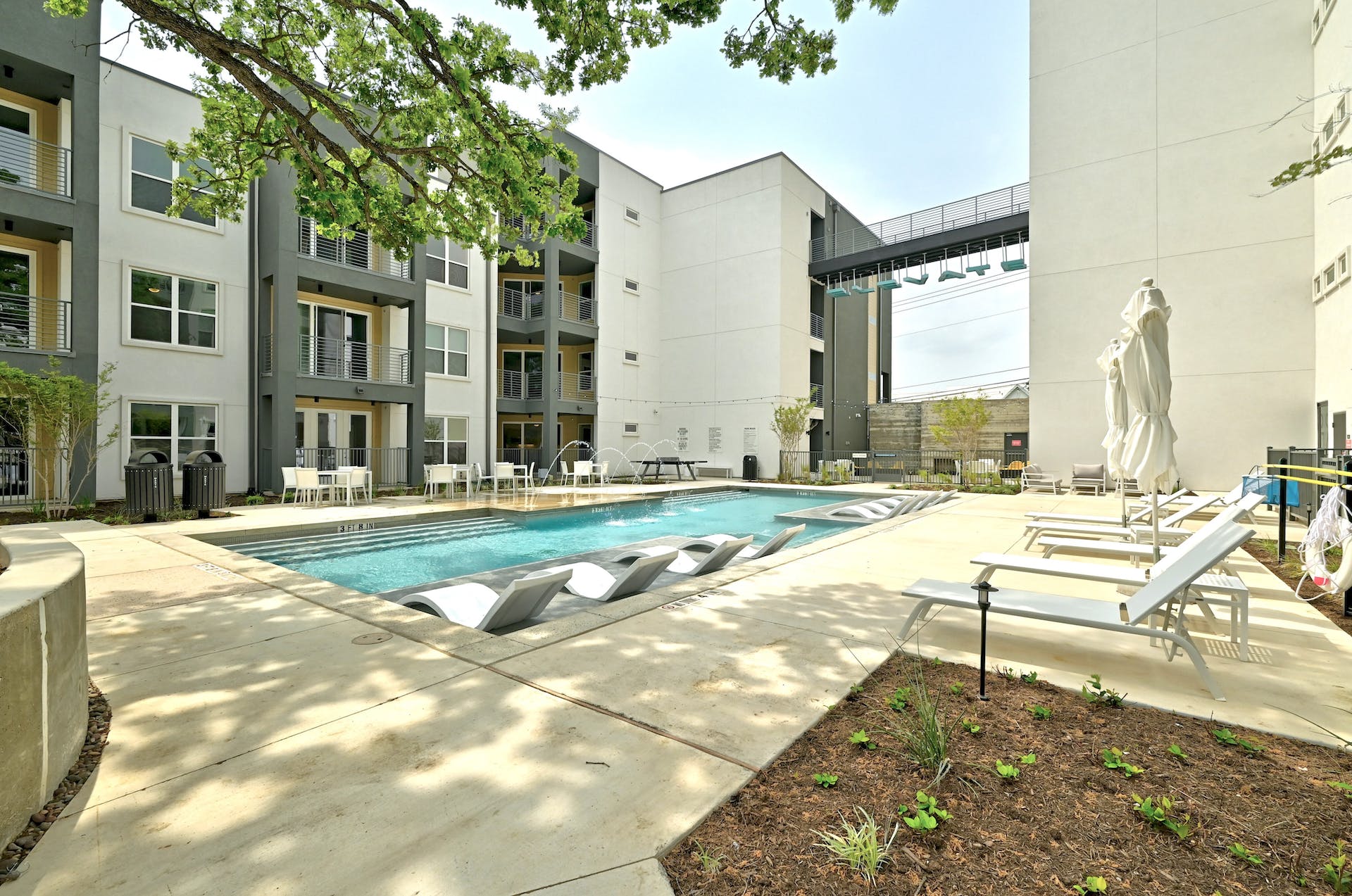 4801 Springdale Road, Unit 1301 Austin, TX 78723 - Photo 26 of 39 A refreshing pool with in-water loungers beckons, surrounded by modern apartment architecture.