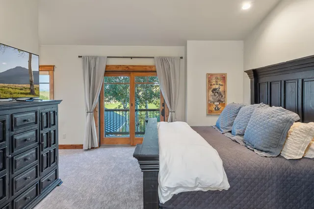 a bedroom with a large bed and a flat tv screen