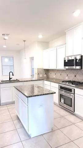 a large kitchen with stainless steel appliances granite countertop a stove top oven a refrigerator and a granite counter tops