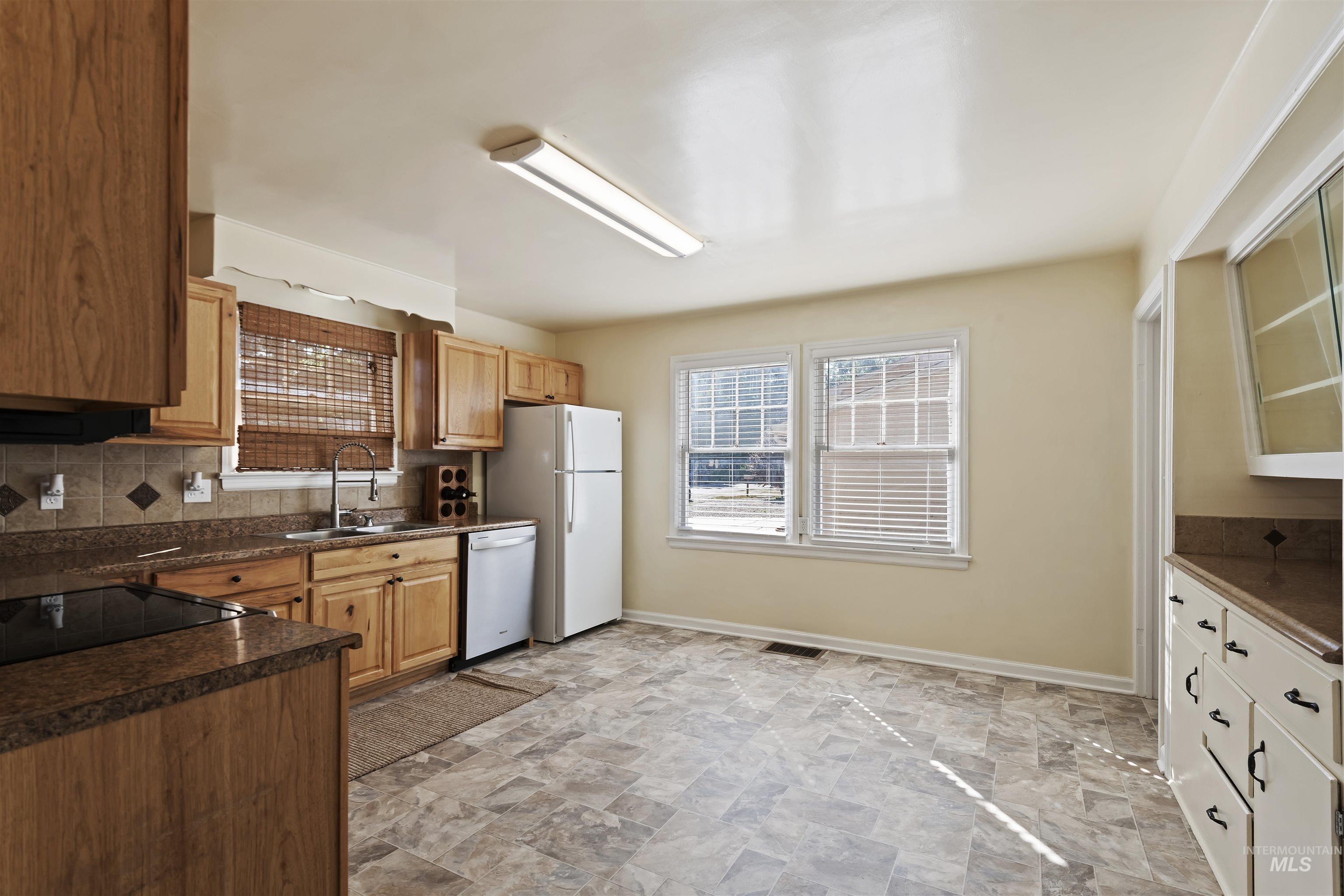 1803 South Arcadia Street Boise, ID 83705 - Photo 12 of 30 Kitchen with dark countertops, backsplash, stone finish flooring, white dishwasher, and glass insert cabinets