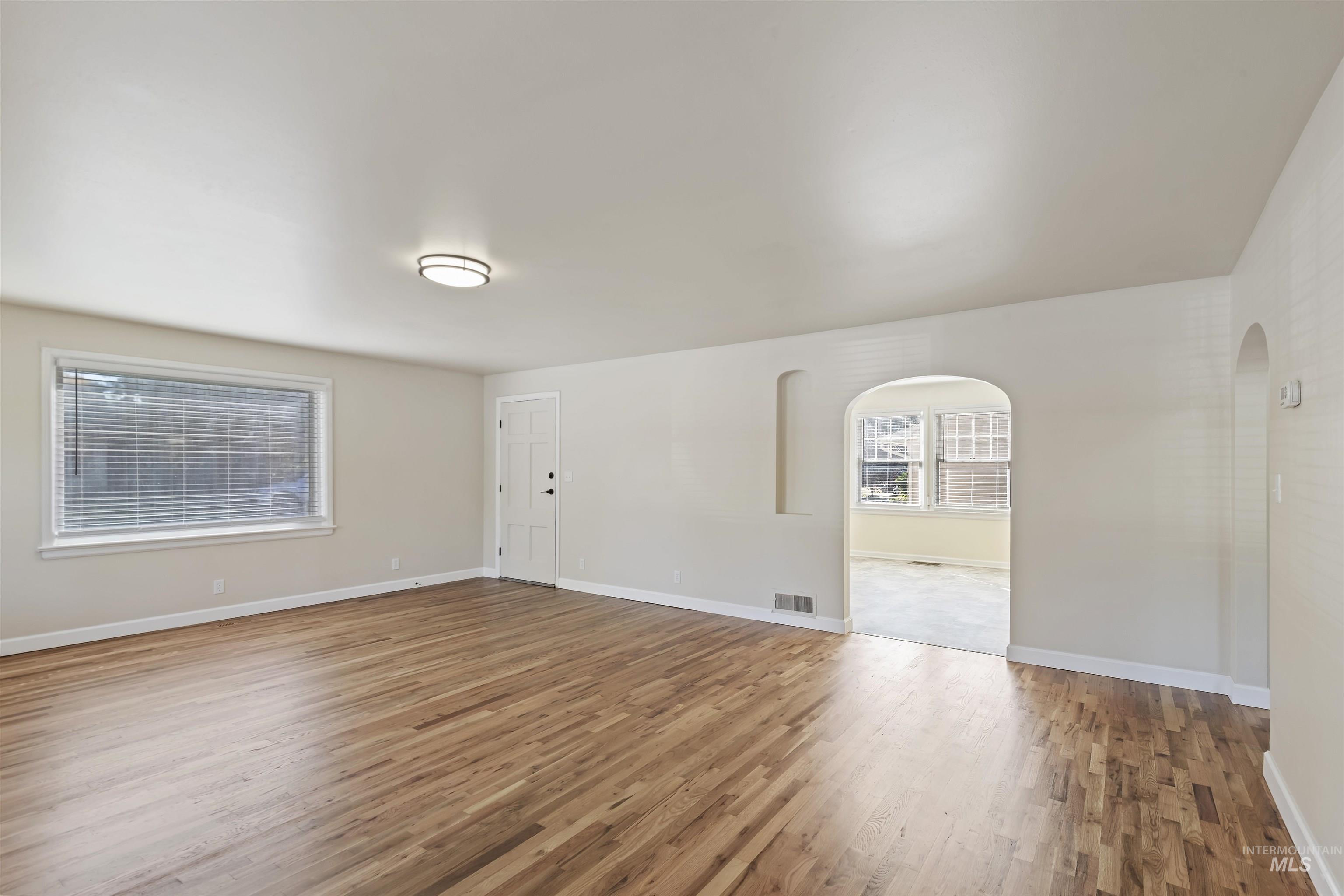 1803 South Arcadia Street Boise, ID 83705 - Photo 6 of 30 Empty room featuring light wood-style floors and arched walkways