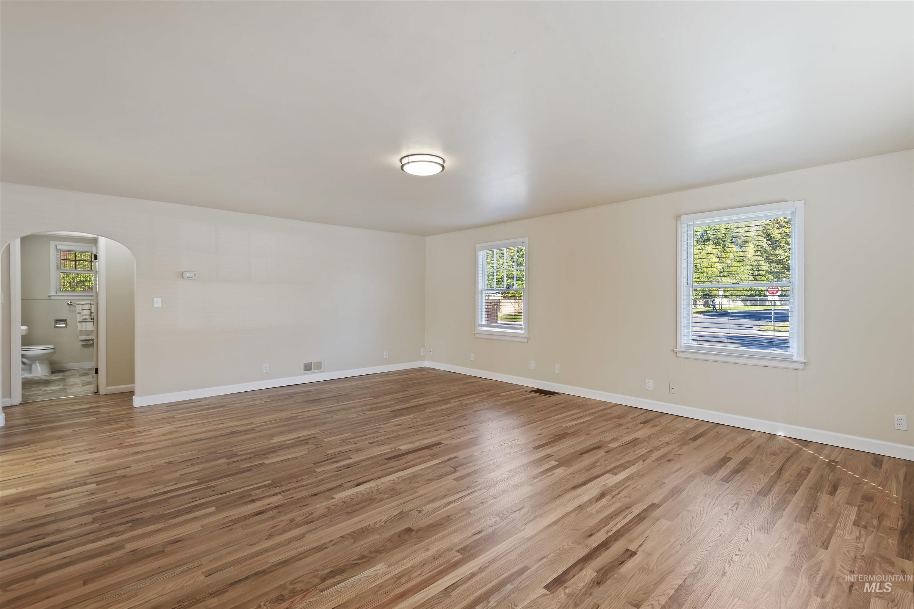 1803 South Arcadia Street Boise, ID 83705 - Photo 8 of 30 Spare room with arched walkways, healthy amount of natural light, and light wood-style floors