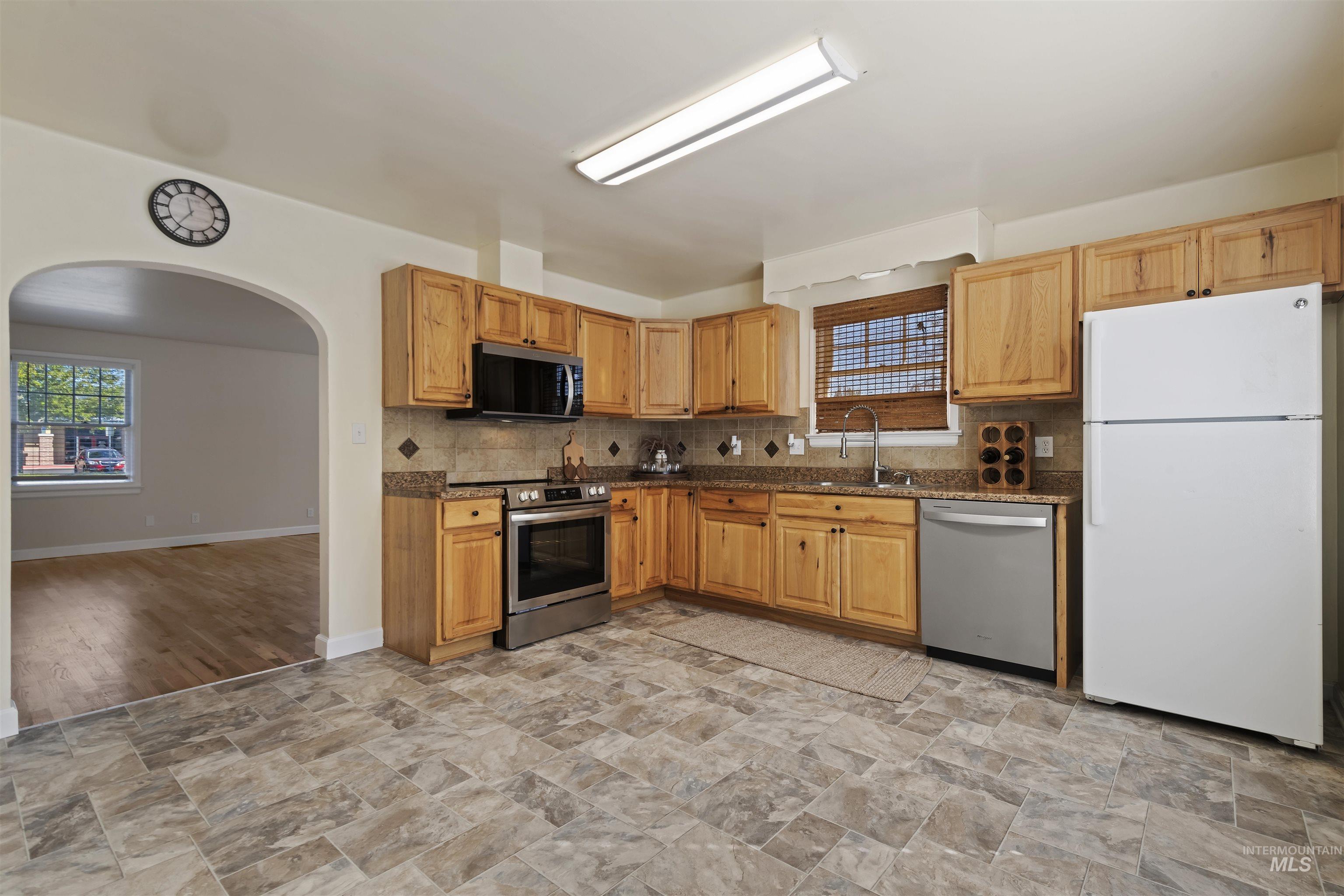1803 South Arcadia Street Boise, ID 83705 - Photo 10 of 30 Kitchen featuring appliances with stainless steel finishes, tasteful backsplash, arched walkways, and stone finish floors