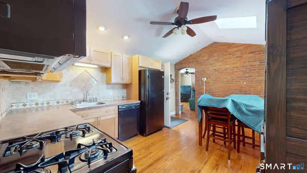 a kitchen with stainless steel appliances granite countertop a stove and a dining table with wooden floor