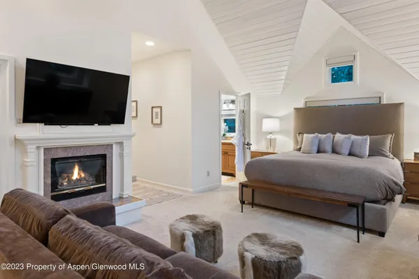 a bedroom with a bed a flat screen tv and a fireplace