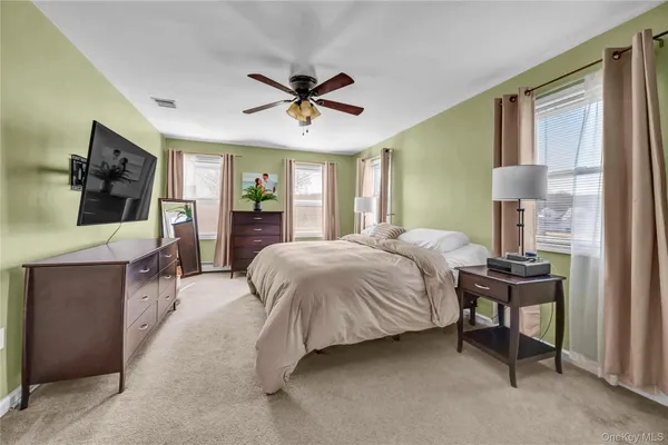 a spacious bedroom with a bed and a flat screen tv