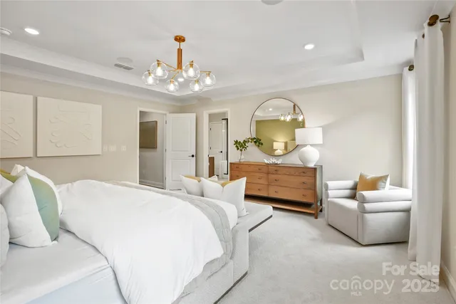 a spacious bedroom with a bed a couch and a chandelier