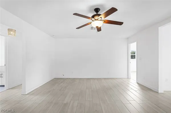 an empty room with wooden floor and ceiling fan