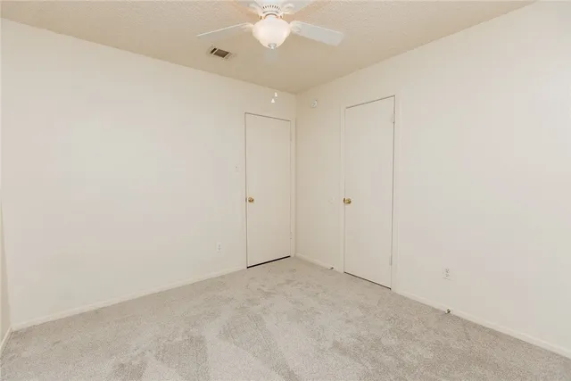 an empty room with a ceiling fan and a window