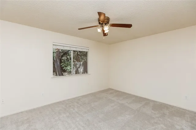 an empty room with a window and ceiling fan