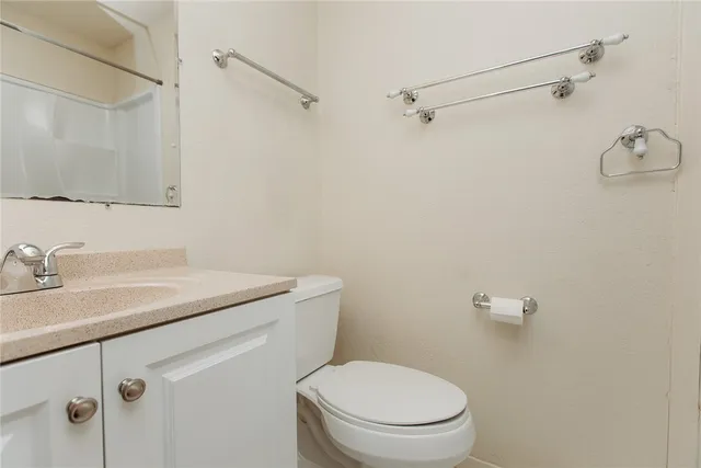 a bathroom with a granite countertop sink a toilet and a mirror