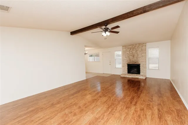 a view of empty room with wooden floor and fireplace