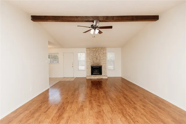 an empty room with wooden floor ceiling fan and windows