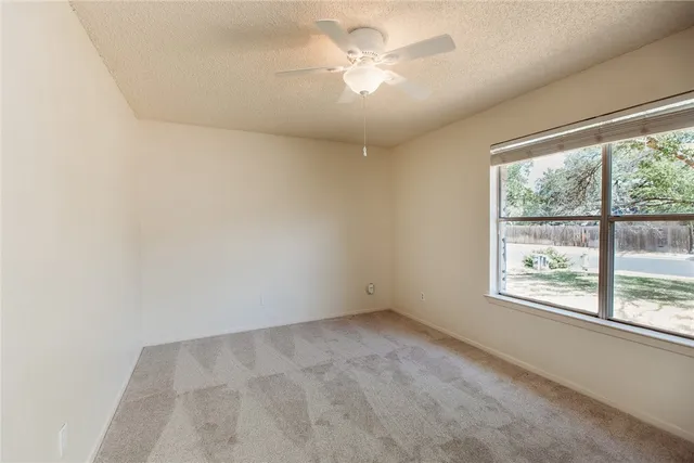 an empty room with a window and a fan