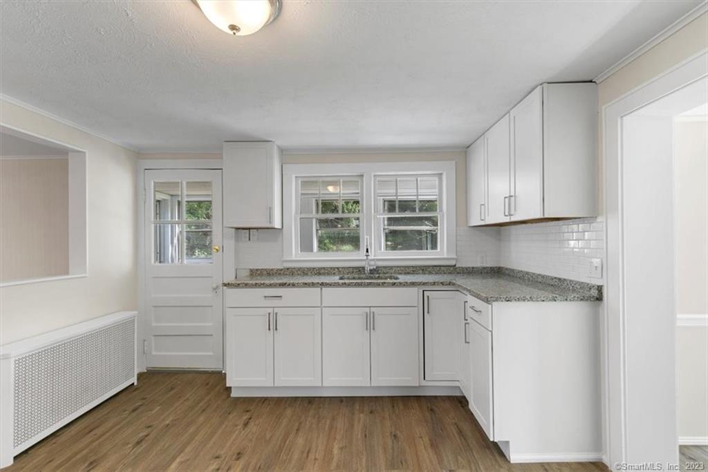1 Chester Avenue Wallingford, CT 06492 - Photo 1 of 1 a kitchen with granite countertop white cabinets and a wooden floor