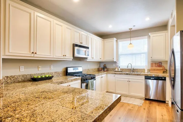 a kitchen with stainless steel appliances granite countertop a refrigerator a stove and a sink
