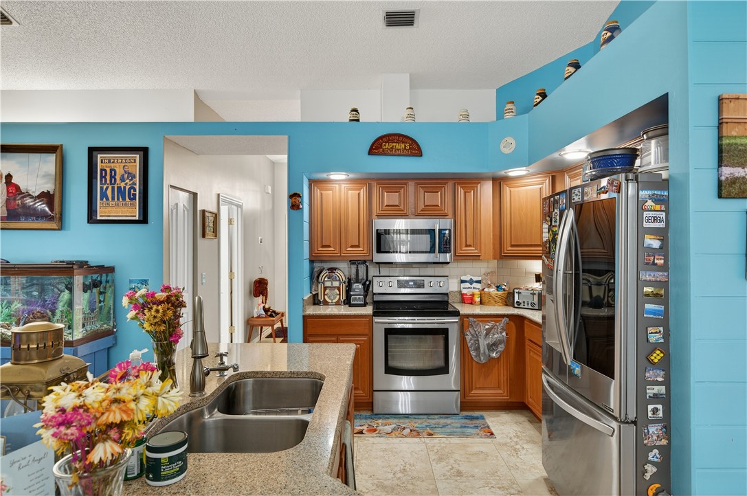 1361 Clearbrook Street Sebastian, FL 32958 - Photo 10 of 29 a kitchen with stainless steel appliances kitchen island granite countertop a sink refrigerator and microwave