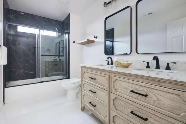 a bathroom with a double vanity sink toilet mirror and shower