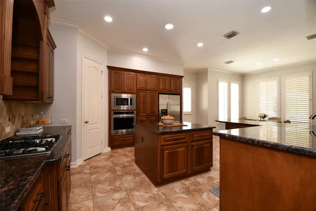a kitchen with stainless steel appliances granite countertop a stove a sink and a refrigerator