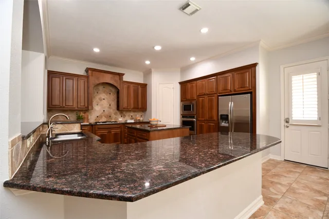 a large kitchen with kitchen island a large counter top stainless steel appliances and cabinets