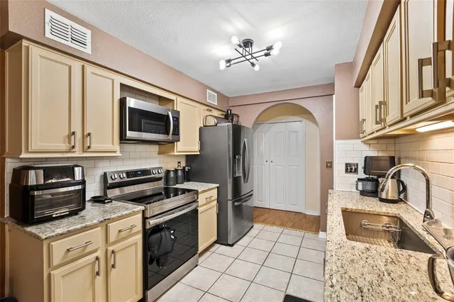 a kitchen with granite countertop a sink stainless steel appliances and cabinets