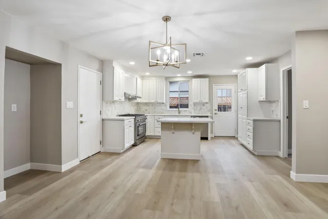 a large white kitchen with lots of counter space wooden cabinets and stainless steel appliances
