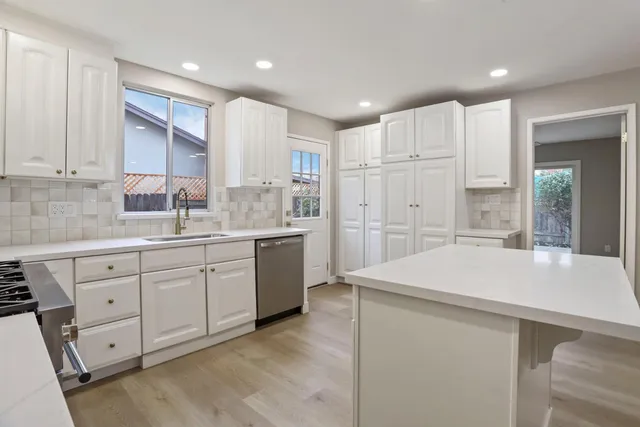 a kitchen with a sink a stove a refrigerator and white cabinets