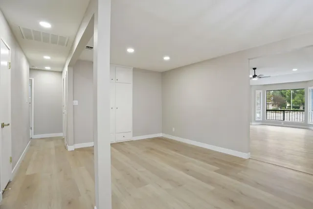an empty room with wooden floor and windows