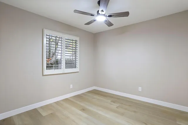 an empty room with a window and a fan