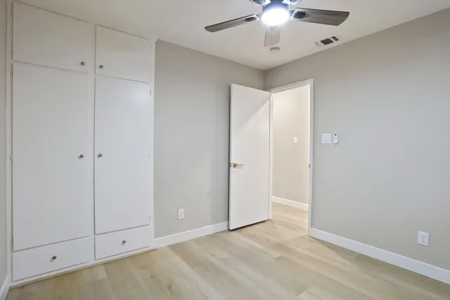a view of an empty room and chandelier fan