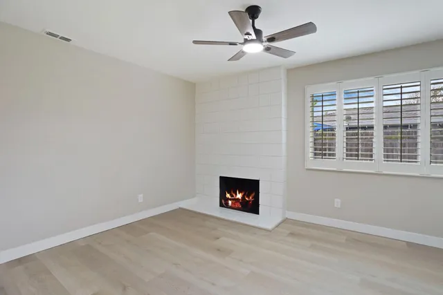 a view of an empty room with a fireplace and a window
