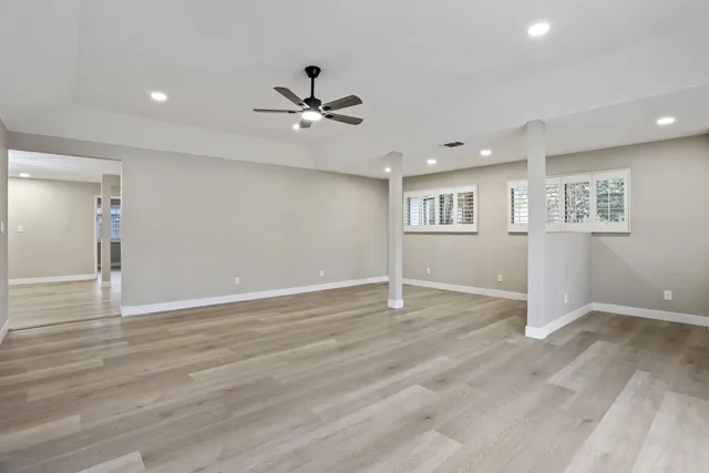 a view of empty room with wooden floor and ceiling fan