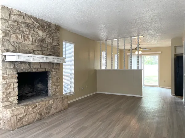 a view of an empty room with wooden floor and a fireplace