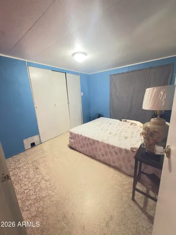 a bedroom with a bed and a dresser with wooden floor