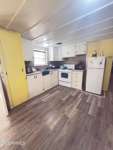 a kitchen with a sink a stove top oven and wooden floor