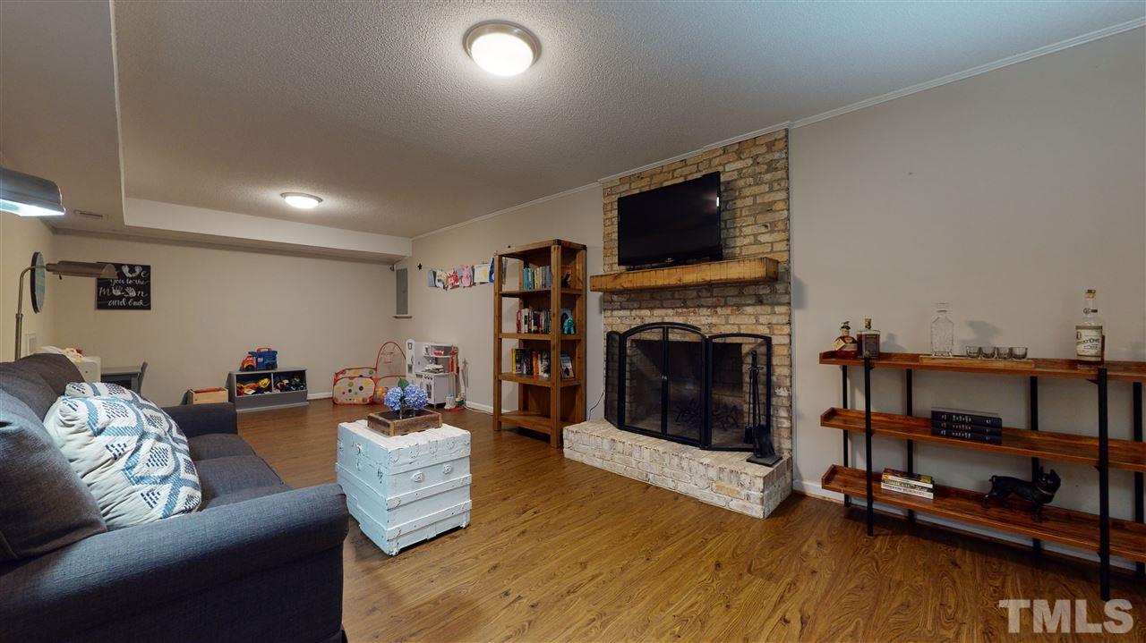 2104 Chrisdale Court Raleigh, NC 27607 - Photo 22 of 29 a living room with furniture a flat screen tv and a fireplace