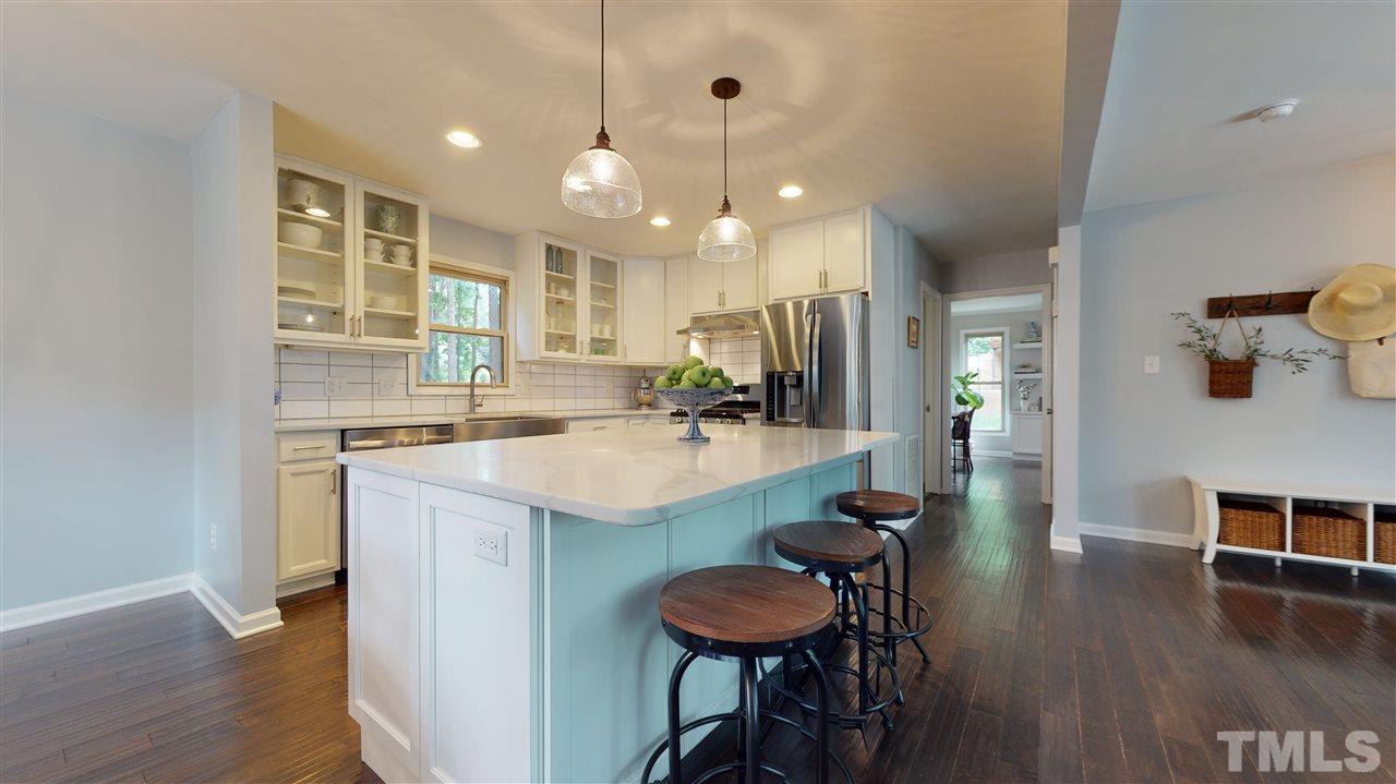 2104 Chrisdale Court Raleigh, NC 27607 - Photo 7 of 29 a kitchen with kitchen island a dining table chairs sink and wooden floor